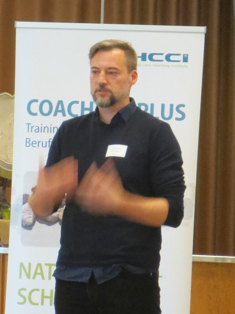 Dr. Andreas Abraham bei einem Vortrag vor einem HCCI-Plakat stehend; Eindrücke vom Networking-Camp Science 1.0 des HCCI, Institut für Supervision in Berlin
